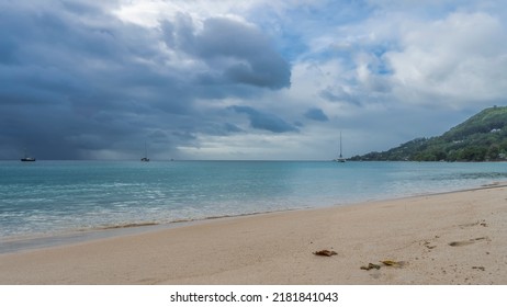 Rain clouds hung over the ocean. Several yachts on turquoise water. A green hill against the sky. Sandy beach in the foreground. Seychelles. Mahe.  Beau Vallon - Shutterstock ID 2181841043
