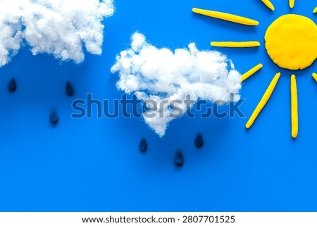 Rain concept. Clouds and drops on blue background top view.