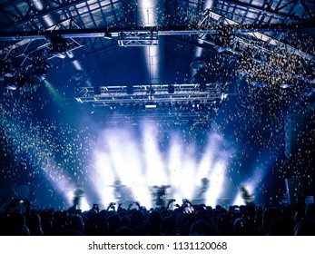 Rain Of Confetti Falling On A Concert Crowd In Front Of A Lit Stage