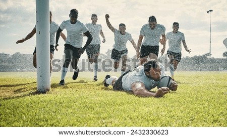 The rain doesnt stop him. Full length shot of a handsome young rugby player scoring a try while training on a rainy day.