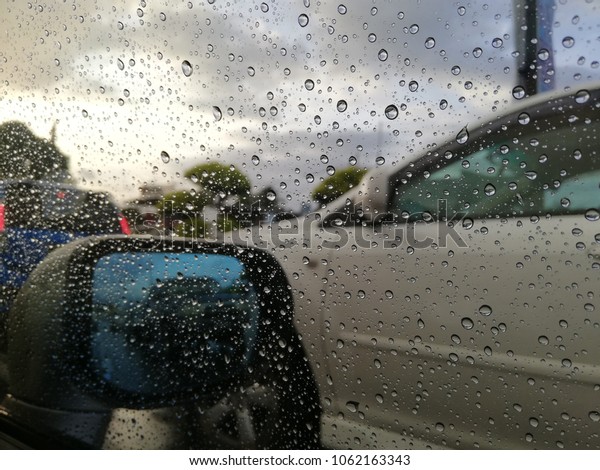 Rain drop bubble on car mirror when raining\
and blur image of car as background use , Rain drop on the car\
glass background