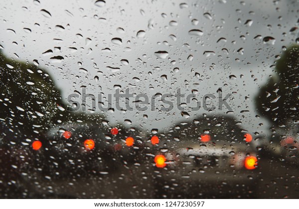 Rain drop on the car glass background.Road\
view through car window with rain drops, Driving in rain.Abstract\
traffic in raining day. View from car\
seat.