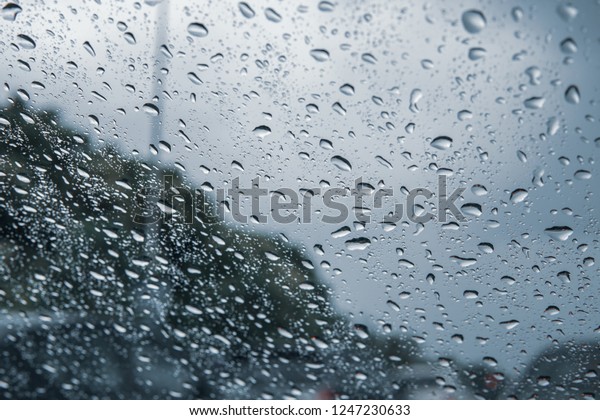 Rain drop on the car glass background.Road\
view through car window with rain drops, Driving in rain.Abstract\
traffic in raining day. View from car\
seat.
