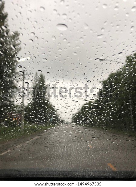 Rain drop on the car glass\
background.Road view through car window with rain drops, Driving in\
rain