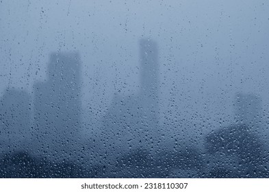 Rain drop on glass window in monsoon season with blurred city buildings background. - Shutterstock ID 2318110307
