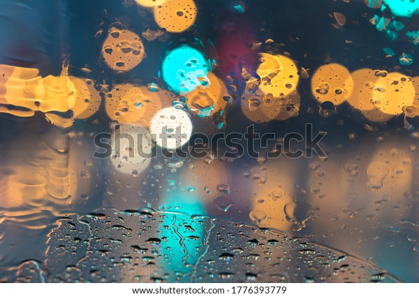 rain droplets on car window street lights are\
making beatifull bokeh