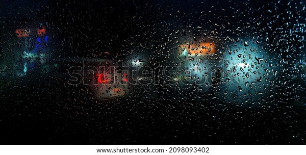 Rain Droplets on car window mirror at night\
in form of wallpaper and background.\
