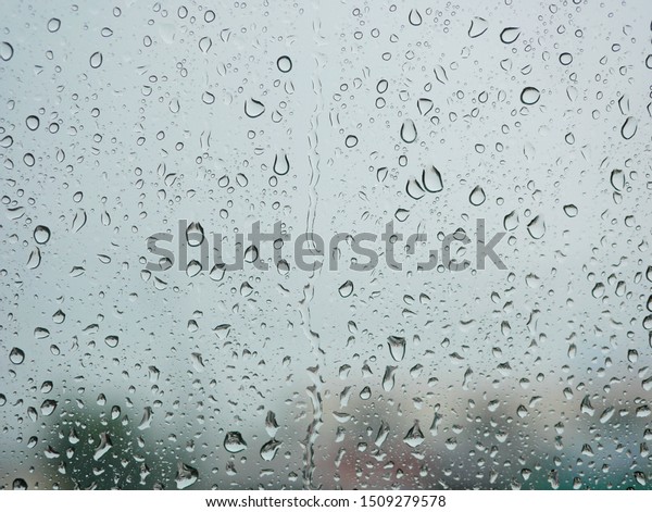 Rain droplets on a car\'s window on a rainy\
day - driver\'s perspective
