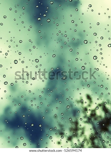 Rain\
droplets on a window pain with sky in the\
background