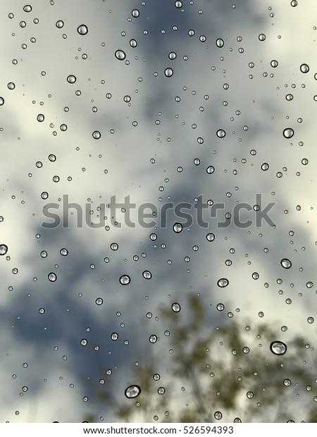 Rain\
droplets on a window pain with sky in the\
background