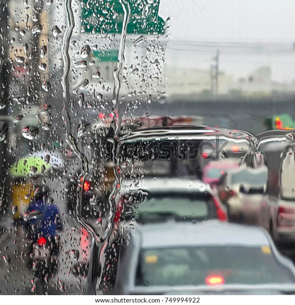 Rain dropping\
on the glass window with traffic jam blur. Rush hour in the rain.\
Life in the rain on busy traffic\
