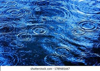 Rain Drops In Blue Surface Water With Ripples Wave 