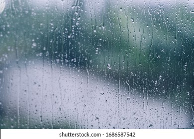 rain drops during raining in rainy day outside window glass with blurred background with water droplet flow down the surface