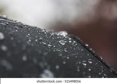 Rain drops fall on a black umbrella close