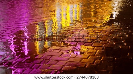 Rain drops falling into puddle on cobblestone street at night, illuminated by pink and orange city lights. Reflections and ripples create a cinematic urban atmosphere with moody, futuristic vibes.