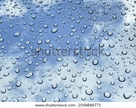 Rain drops at mirror with cloudy blue sky