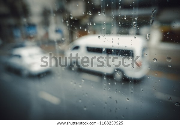 Rain drops on car window with road light bokeh.\
Stock image of rain drops on car glass in rainy season abstract\
background, water drop on the glass, night storm raining car\
driving concept