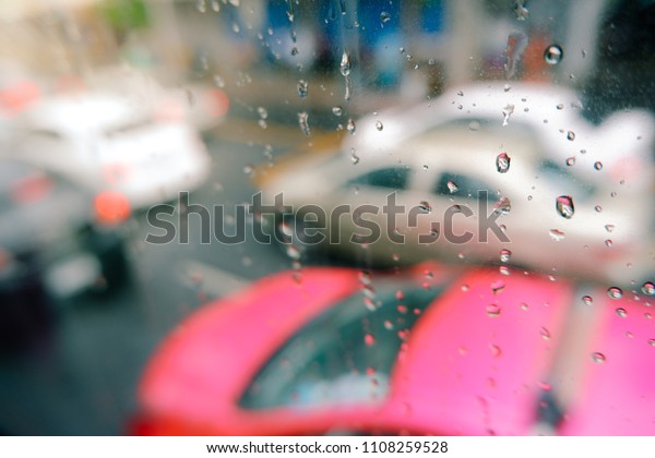 Rain drops on car window with road light bokeh.\
Stock image of rain drops on car glass in rainy season abstract\
background, water drop on the glass, night storm raining car\
driving concept