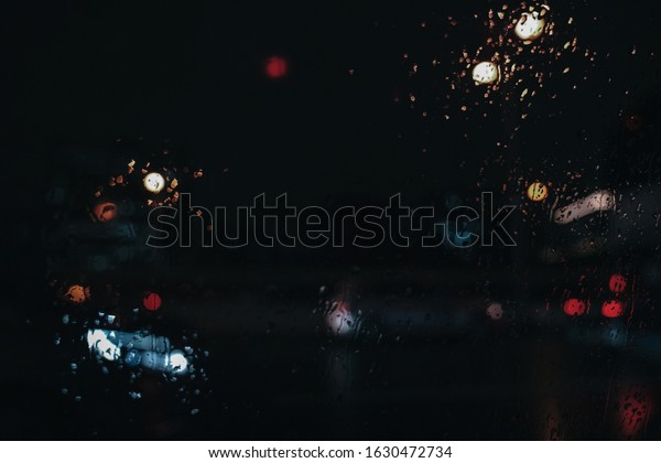 Rain drops on car\
window with road light bokeh, City life in night in rainy season\
abstract background,water drop on the glass, night storm raining\
car driving concept.