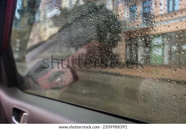Rain drops on car window. Rainy day from car cabin. Rain\
drops on car mirror. Travel by auto. Wet car glass. Bad autumn\
weather. 