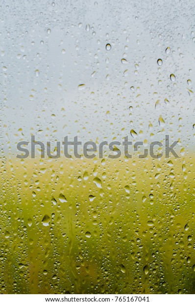 Rain\
drops on car window with blur paddy field\
background