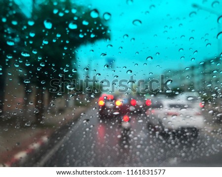 Rain Drops on the car windshield, traffic in the city on a rainy day at evening, colorful bokeh, blurry background.
