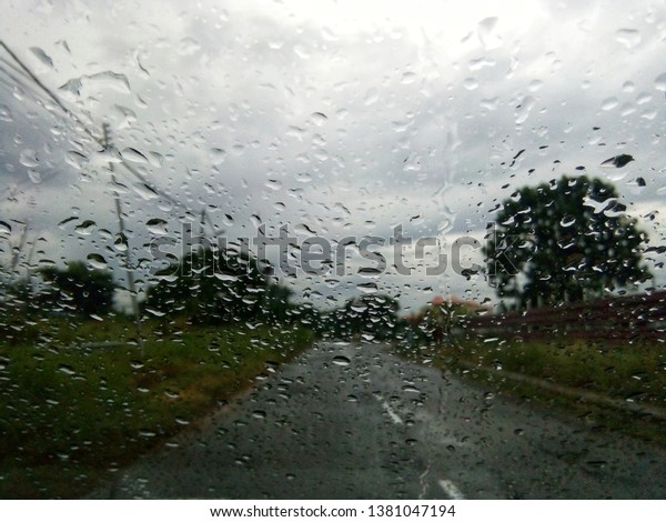 Rain drops on glass car window with road light\
bokeh. Stock image of rain drops on car glass in rainy season\
abstract background, water drop on the glass, night storm raining\
car driving concept
