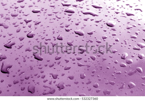 Rain drops on purple metal\
surface with blur effect. Abstract background and texture for\
design.