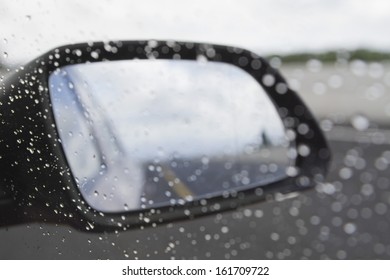 Rain drops on the side-view mirror of a car