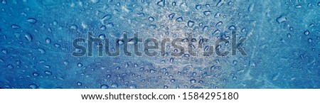 Rain drops on the surface of the blue waterproof fabric. The view from the bottom up.