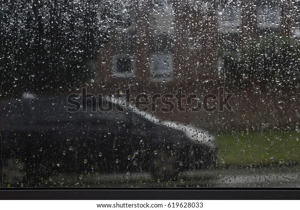 Rain drops on transparent window with a black\
cab in the background