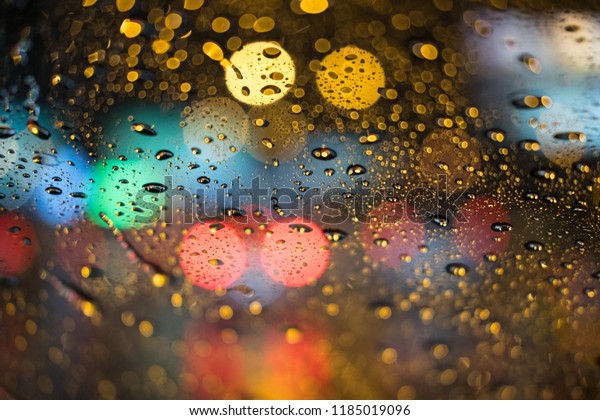 Rain\
drops rain on the window with blurred traffic\
light