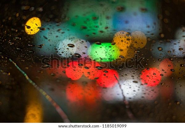 Rain\
drops rain on the window with blurred traffic\
light