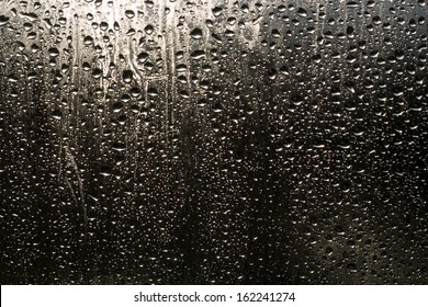 Rain drops on the window on the dark background