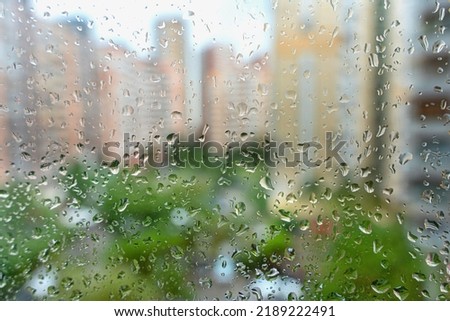 Rain drops on a window with a defocused cityscape.