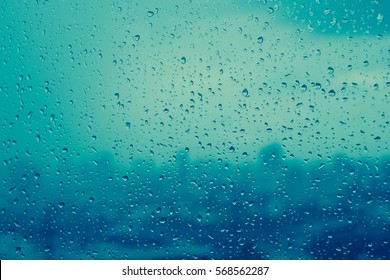 Rain drops on window glass outside texture background water of wonderful heavy rainy day with sky clouds at city blue green blurred lights abstract view sunshine enjoy the relaxing nature wallpaper