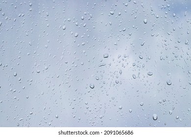 Rain drops on window glasses surface with gray sky background. Natural backdrop of raindrops. Abstract overlay for design. The concept of bad rainy weather. - Powered by Shutterstock