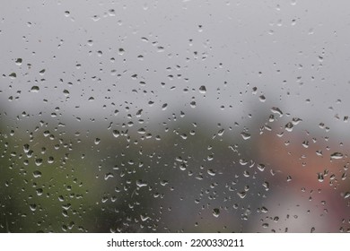 Rain drops on the window glasses surface with nature background. Wet window glass with splashes and drops of water. Cold autumn thunderstorm concept. Natural pattern of raindrops. Autumn window view. - Shutterstock ID 2200330211