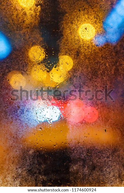 Rain drops on the window in the night city.\
Blurred vertical\
background