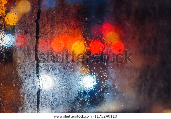Rain drops on the window in the night city.\
Blurred background