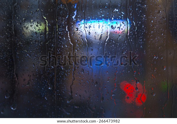 Rain drops on window - night light.\
Drops and\
trickles of water on glass surface, blurred urban background,\
colorful neon lights