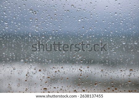 Rain drops are on the windowpane. On this gloomy, rainy day, it's hard to believe that you can see the sky and the Baltic Sea outside the window. This view is from a window in Mielno, Poland.