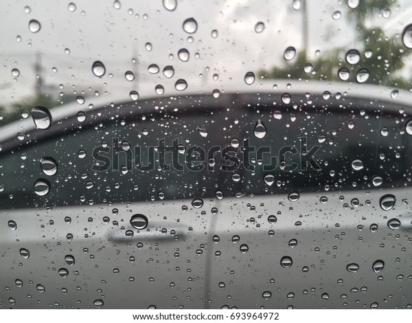 Rain drops on windows with car\
background. Close up. Blurred background. Rainy season in\
Thailand.
