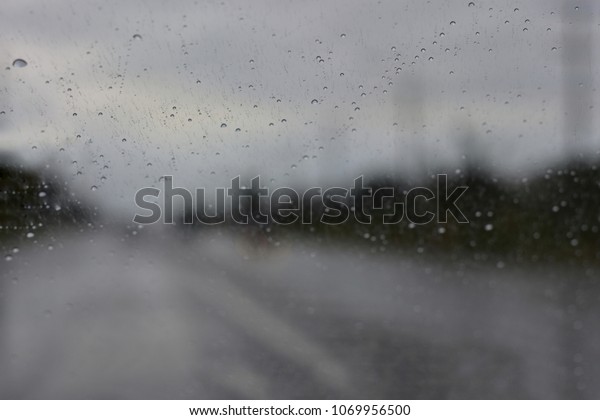 Rain drops on the windshield\
make bad visibility, be careful in driving, the road safety\
concept.