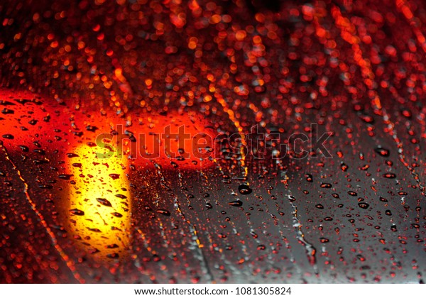 Rain drops in raining day on\
window car with street Bokeh Light Out Of Focus, City nightlife in\
rainy season.Water drop on the glass,abstract\
background.