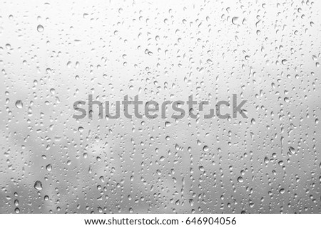 Rain drops, water drops of rain on a window glass. blurred lights city with sky clouds in rainy day, abstract blue background texture, view beautiful from outside window