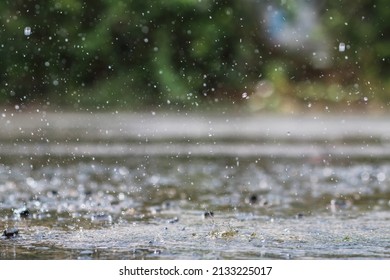 Rain is falling heavily due to sudden thunderstorms and summer storms, causing the downpours to not be able to drain quickly into the sewers, causing rain water to pool on the road surface. - Shutterstock ID 2133225017