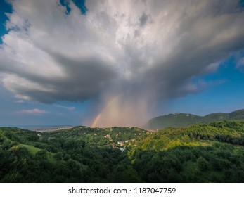 Rain falling from an white cloud with the rainbow beneath it.