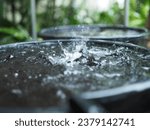 Rain falls into the bucket, causing the water to splash.