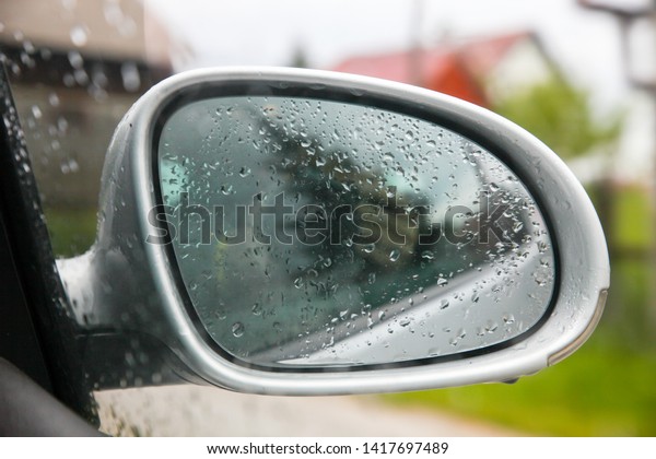 Rain falls on the rearview\
mirror and glass,reflection photographer in the rearview\
mirror.-Image